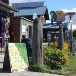 A woman sits on a bench outside The Better Sweater on Labor Day. Although some places will remain open until next week and the last visit on Tuesday of the cruise ship Statendam, many Spit stores and restaurants closed on Monday.