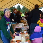 Margarida Kondak sells tickets for a turkey raffle at last Saturday’s end-of-season party at the Homer Farmers Market. Behind her, volunteers serve free soup, bread and desserts to shoppers.-photo by Annie Rosenthal