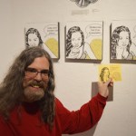 Artist Brian Payne poses with his tryptich at Bunnell Street Art Center’s 10x10 show opening on Nov. 20. The piece was inspired by a comic strip he created that includes a haiku written by his wife, Skywalker Payne.-Annie Rosenthal, Homer News