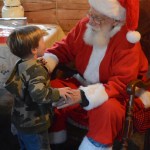 Santa Claus visits with Ryder Donahue at the Harrington Cabin during the Pratt Museum Stocking Stuffer Party last Saturday. Ryder is from Eagle River and was visiting his grandparents in Homer.