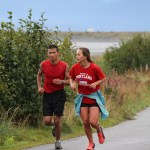 Kane Graham and Lauren Kuhns keep pace with each other as they run back down the Spit, making their way back to the high school where the finish line for the three-part race was located.  Graham finished second overall in the triathlon and Kuhns finished third overall, three seconds behind Graham.