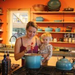 Eve Kilcher stirs a pot of chicken soup while holding Sparrow. The Kilcher's kitchen, which is the backdrop of the cover photo on Homestead Kitchen, was under construction for the majority of the time the Kilchers worked on the cookbook.-Photo by Anna Frost, Homer News