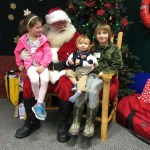 Imogen Richardson, age 7, and her brothers Erik, 1, and Lewis, 9, visit with Santa during Nomar's annual holiday open house on Sunday. Their parents are Steven and Jenna Richardson. The family is from County Mayo in Ireland and is living in Homer while Steven Richardson studies at Alaska Bible Institute.-Photo by Lori Evans, Homer News