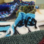 Booties, scarves, hats and more cover a table during a meeting of the Wildwood Correctional Complex's crochet program Tuesday, Nov. 29 at the complex's pretrial building in Kenai. Some of the items made by inmates are sent to Homer Thrift, where they are sold. The proceeds benefit the Child Advocacy Centers in Homer and Kenai.-Photo by Megan Pacer, Morris News Service - Alaska