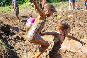 Photo by Megan Pacer/Homer News McKenna Connelly, left, plunges into an especially deep pocket of muddy water while holding tight to Alivia Craddock&rsquo;s hand Saturday, July 22, 2017 during the annual Mud Wallow held at Cottonwood Horse Park in Homer, Alaska. Hosted by the organization Nature Rocks, the messy event is in its eighth year.