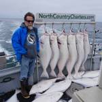 Michael Armstrong stands by a rack of halibut on the Irish as the North Country Charters boat returns to Homer, Alaska. He caught two of the smaller fish on the deck. The 16 fishermen on the 53-foot boat all limited out on a July 16, 2017 guided halibut fishing trip. Photo by Øisten Stokke Berget