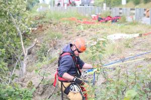 Aaron Glidden, a member of Kachemak Emergency Services, makes his way down the slope near Baycrest Overlook on Monday, July 24, 2017 in Homer, Alaska. First responders found a pickup truck that had fallen over the edge after hitting a guard rail on the Sterling Highway, and searched for a possible victim until getting a report that the driver had crashed several days earlier and had walked away uninjured. Photo by Megan Pacer/Homer News