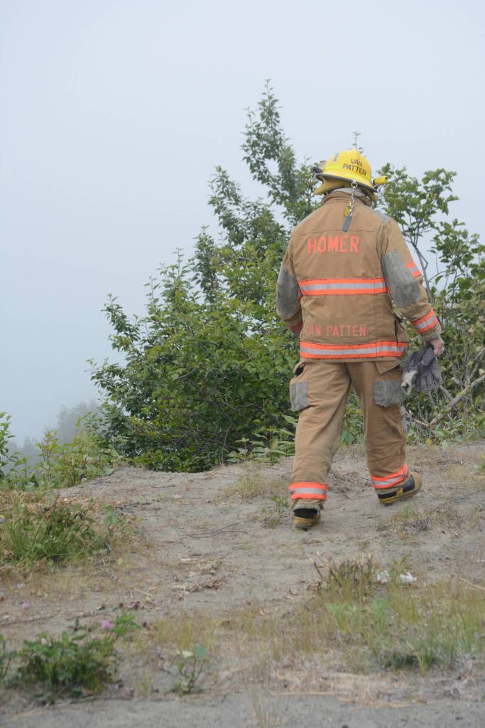 Homer Volunteer Fire Department firefighter Doug Van Patten checks out the edge of the bluff where Thayr Watson&rsquo;s truck went over the edge sometime over the weekend during a search Monday, July 24, 2017 in Homer, Alaska. Photo by Michael Armstrong/Homer News