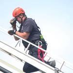 Joe Sallee, Deputy Chief at Kachemak Emergency Services, uses binoculars at the end of a ladder extended from the KES ladder truck to search the slope near Baycrest Overlook on Monday, July 24, 2017 in Homer, Alaska. First responders found a pickup truck that had fallen over the edge after hitting a guardrail, and searched for a possible victim until getting a report that the driver had crashed several days earlier and had walked away uninjured. Photo by Megan Pacer/Homer News
