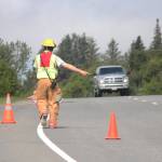 A first responder directs an oncoming truck around the cones set out to give crews space while they responded to a report of a truck that had fallen over the edge near Baycrest Overlook on Monday, July 24, 2017 in Homer, Alaska. First responders found the pickup truck that had fallen over the edge after hitting a guardrail, and searched for a possible victim until getting a report that the driver had crashed several days earlier and had walked away uninjured. Photo by Megan Pacer/Homer News