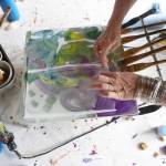 Ann-Margret Wimmerstedt demonstrates making an encaustic monoprint on an encaustic painting palette July 30, 2017 at Wimmerstedt&rsquo;s home. A hot plate, the palette is where blocks of pigmented wax are mixed with encaustic media made of beeswax and damar, a pine resin. Paper placed over the hot wax and pigment can make a print. (Photo by Michael Armstrong/Homer News)