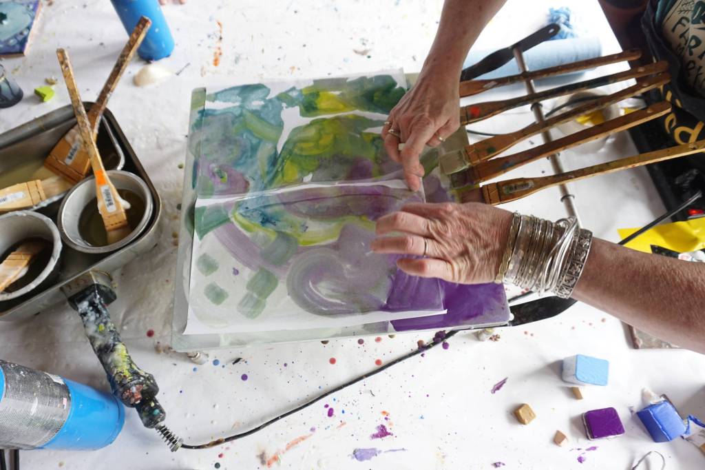 Ann-Margret Wimmerstedt demonstrates making an encaustic monoprint on an encaustic painting palette July 30, 2017 at Wimmerstedt&rsquo;s home. A hot plate, the palette is where blocks of pigmented wax are mixed with encaustic media made of beeswax and damar, a pine resin. Paper placed over the hot wax and pigment can make a print. (Photo by Michael Armstrong/Homer News)