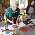 Ann-Margret Wimmerstedt paints with encaustics on July 30, 2017 at Wimmerstedt&rsquo;s home. &ldquo;Encaustics&rdquo; means &ldquo;to burn,&rdquo; and is the art technique of using pigmented hot wax to paint. Artist Carla Klinker-Cope, right, watches. (Photo by Michael Armstrong/Homer News)