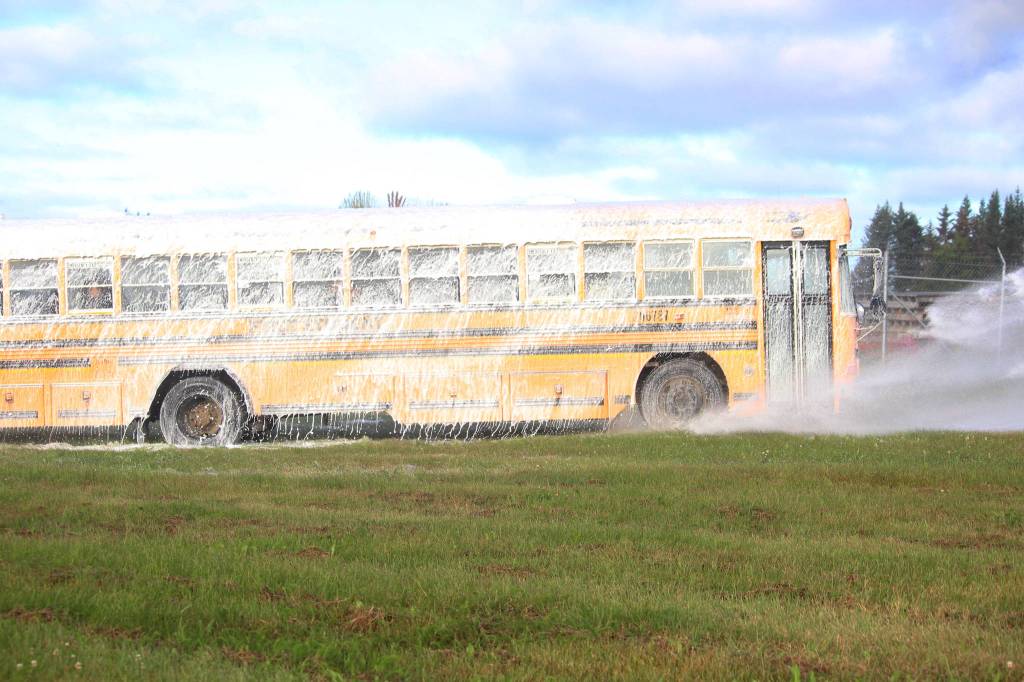 A bus being used for a simulated airplane crash exercise is sprayed down with foam during the drill Saturday, Aug. 19, 2017 at the Homer Airport in Homer, Alaska. The drill is required every three years and tests the ability of airport personnel and local emergency responders to handle various emergency scenarios. (Photo by Megan Pacer/Homer News)