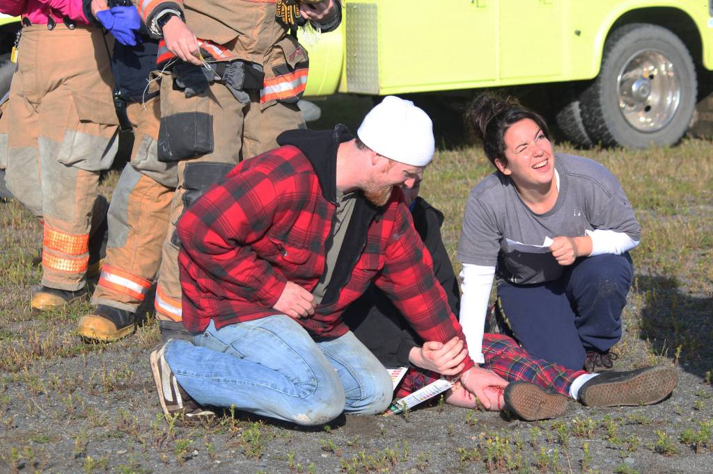 Stephen Rainwater (left) and Jaclyn Rainwater (right) hold onto a fake wound on Ben Rainwater&rsquo;s leg during a simulated plane crash exercise Saturday, Aug. 19, 2017 at the Homer Airport in Homer, Alaska. They were some of more than 20 volunteers who turned out to pose as crash victims during the drill that takes place at the airport every three years. (Photo by Megan Pacer/Homer News)