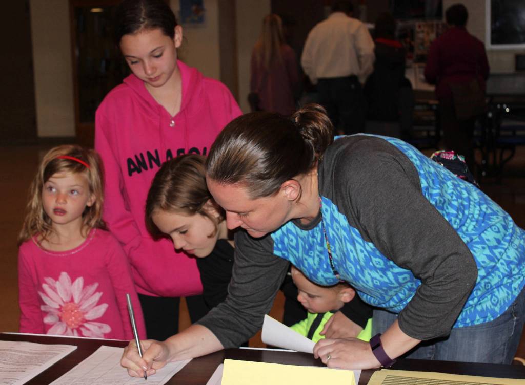 Brienne Kozloski signs her children up for youth basketball offered through city of Homer Community Recreation. The sign-up was offered at the Aug. 16 Youth After School Activities and Programs event sponsored by K-Bay Community Youth and Activities Coalition. From left: Cassidy, Madeline, Bayleigh and, Kozloski, and Michael peeking under Kozloski&rsquo;s arm. (Photo by McKibben Jackinsky for the Homer News)