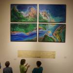 Visitors to the Pratt Museum look at &ldquo;Wild Alaska,&rdquo; above, by Karla Moss Freeman, and a 1900 map of the Cook Inlet Coal Fields railroad, one of the historic pieces included in cARTography exhibit Tuesday, Aug. 22, 2017 at the Pratt Museum, Homer, Alaska. (Photo by Michael Armstrong, Homer News)