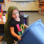 Olivia Pitzman, a kindergartener, carries her tub of outside clothes to a desk as she prepares to head outdoors for recess on the first day of the school year Tuesday, Aug. 22, 2017 at Paul Banks Elementary in Homer, Alaska. (Photo by Megan Pacer/Homer News)