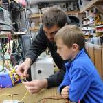 In a good example of building the next generation of marine trades-related professionals, Mark Zeiset, owner of South Central Radar, teaches his son Finn, 6, how to test fuses. (Photo by McKibben Jackinsky for the Homer News)