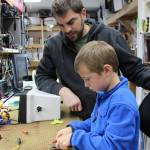 In a good example of building the next generation of marine trades-related professionals, Mark Zeiset, owner of South Central Radar, teaches his son Finn, 6, how to test fuses. )Photo by McKibben Jackinsky for the Homer News)