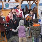 Erin Searcy-Dudgeon Wells of Rogues & Wenches, center, leads a sing along at the Kachemak Bay Wooden Boat Society Festival on Saturday, Sept. 2, 2017 at the Nick Dudiak Fishing Lagoon campground in Homer, Alaska. At left are Lucia Woofter and Lena Gonzales. At far right is Hunter Woofter, Devin Frey, second from right, and Bob Woofter. (Photo by Michael Armstrong, Homer News)