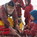 John Miles, left, helps Ike Mitchell work on a boat during the Kachemak Bay Wooden Boat Society Festival on Saturday, Sept. 2, 2017 at the Nick Dudiak Fishing Lagoon campground in Homer, Alaska. Ike&rsquo;s mother, Jamey Cloud, and his brother, Charlie Mitchell, watch. (Photo by Michael Armstrong, Homer News)