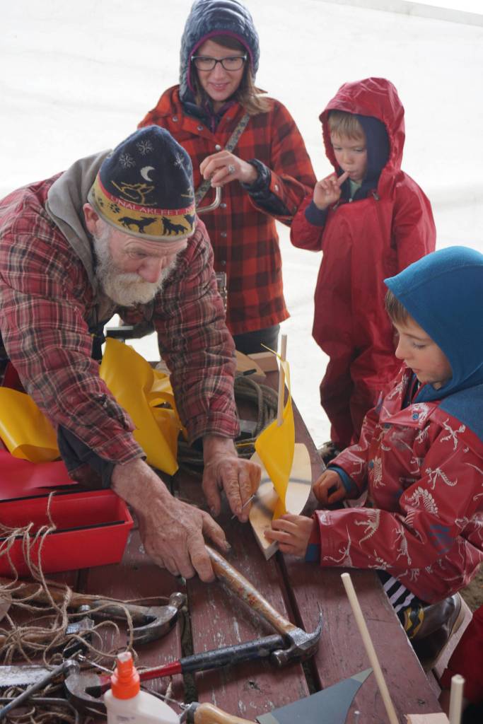 John Miles, left, helps Ike Mitchell work on a boat during the Kachemak Bay Wooden Boat Society Festival on Saturday, Sept. 2, 2017 at the Nick Dudiak Fishing Lagoon campground in Homer, Alaska. Ike&rsquo;s mother, Jamey Cloud, and his brother, Charlie Mitchell, watch. (Photo by Michael Armstrong, Homer News)