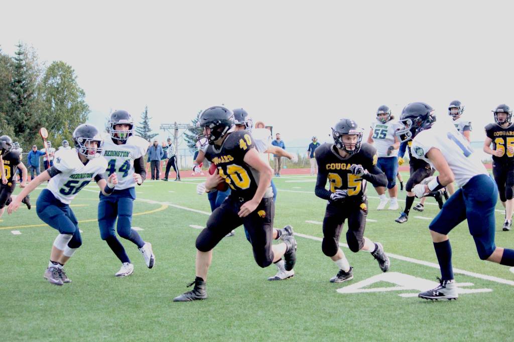 Cougars quarterback Anthony Kalugin (center) and junior Kalinik Reutov (#25), face off against players from Joe Redington Jr/Sr High School on Friday, Sept. 15, 2017 at Homer High School in Homer, Alaska. (Photo by Megan Pacer/Homer News)