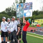 Cougars Head Coach Justin Zank helps hold up a sign to communicate plays to his team during their game against Nikiski High School on Saturday, Sept. 2, 2017 in Homer, Alaska. Zank uses pictures to represent the names of plays. One sign Saturday contained a play written in Cyrillic. (Photo by Megan Pacer/Homer News)