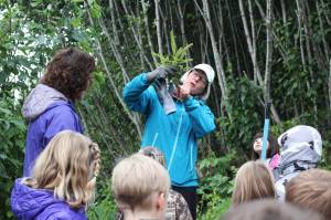 Deb Lowney demonstrates to a group of Paul Banks Elementary students how much of a tree&rsquo;s roots need to be buried in the ground when they are transplanted Thursday, Sept. 7, 2017 at Karen Hornaday Park in Homer, Alaska. The students volunteered to transplant the pine trees onto new trail sections at the park to promote plan diversity. (Photo by Megan Pacer/Homer News)