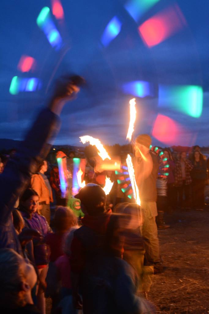 Revelers spin LED lighted poi at Shine, the 2017 Burning Basket, as it burns on Sunday, Sept. 10, 2017 at Mariner Park on the Homer Spit. (Photo by Michael Armstrong, Homer News)