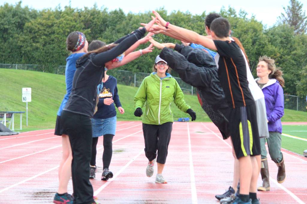 Saundra Hudson, an active member of and advocator for the Homer running community and teacher at Homer High School, runs under a human bridge during the Mariner Mile event Thursday, Sept. 14, 2017 at the high school track in Homer, Alaska. Hudson experienced a head injury when she slipped on the ice running this past March, and Thursday&rsquo;s fundraising event for the Kachemak Bay Running Club was the first time she&rsquo;s run in six months. (Photo by Megan Pacer/Homer News)