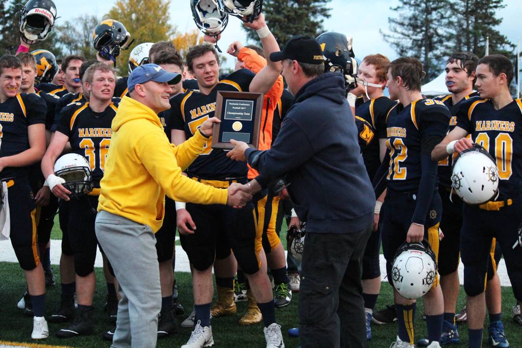 Homer High School Athletic Director Chris Perk presents Walter Love, head coach for the Homer Mariner varsity football team, with a plaque celebrating the team&rsquo;s status as Division III Peninsula Conference champs after their game Friday, Sept. 29, 2017 at the high school in Homer, Alaska. This is the first Peninsula Conference title for the Mariners. (Photo by Megan Pacer/Homer News)