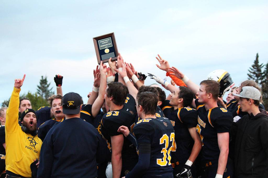 Members of the Homer Mariner varsity football team cheer and hoist their Division III Peninsula Conference title plaque into the air after their game against the Head of the Bay Cougars on Friday, Sept. 29, 2017 at their home field in Homer, Alaska. The Mariners clinched their first conference title after winning their Sept. 22 game against Joe Redington Sr High School. (Photo by Megan Pacer/Homer News)