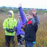 Paul Banks Elementary students Gabe Stanislaw (left), Tatum Kirtley (center) and Isaiah Mann (right) raise their hands to answer a questions during a field trip to the Beluga Slough on Thursday, Sept. 28, 2017 in Homer, Alaska. (Photo by Megan Pacer/Homer News)