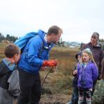 Seth Spencer from the Center for Alaskan Coastal Studies teaches Trygg Flyum (left), Tristan Alward (background), Tatum Kirtley (center) and their classmates about decomposing fish and what they mean for the Beluga Slough during a field trip there Thursday, Sept. 28, 2017 in Homer, Alaska. (Photo by Megan Pacer/Homer News)