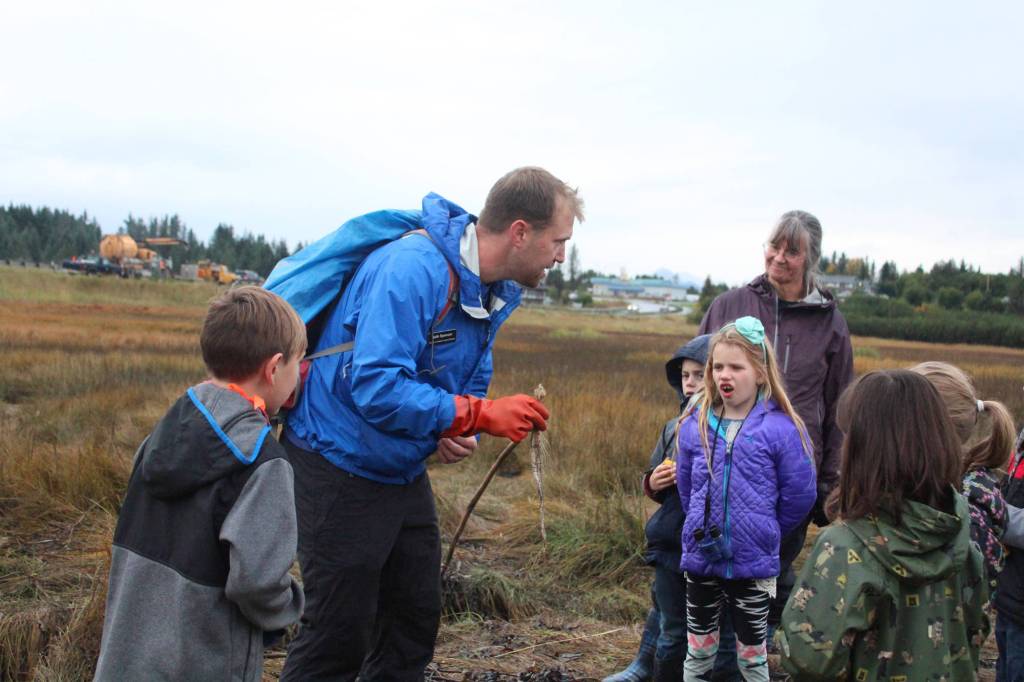 Seth Spencer from the Center for Alaskan Coastal Studies teaches Trygg Flyum (left), Tristan Alward (background), Tatum Kirtley (center) and their classmates about decomposing fish and what they mean for the Beluga Slough during a field trip there Thursday, Sept. 28, 2017 in Homer, Alaska. (Photo by Megan Pacer/Homer News)