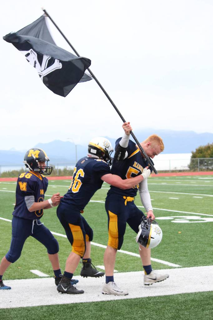 Senior Levi Smith gets a hug from a teammate as he walks of the field at Homer High School carrying a pirate flag Saturday, Oct. 7, 2017 following the varsity football team&rsquo;s win over Ben Eielson High School 33-21 in Homer, Alaska. The Mariners now head to the ASAA First National Bowl Series Division III Championship. (Photo by Megan Pacer/Homer News)