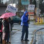 Wayne Aderhold, right, waves signs for Linda Hutchings on Tuesday afternoon, Oct. 24, 2017, in Homer, Alaska, on Pioneer Avenue. To his left are Marjorie Ringer, with umbrella, Lani Raymond and Ron Keffer. (Photo by Michael Armstrong, Homer News)