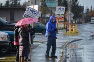 Wayne Aderhold, right, waves signs for Linda Hutchings on Tuesday afternoon, Oct. 24, 2017, in Homer, Alaska, on Pioneer Avenue. To his left are Marjorie Ringer, with umbrella, Lani Raymond and Ron Keffer. (Photo by Michael Armstrong, Homer News)