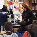 Laura Murphy, a teacher at Razdolna School, presents Chris Mburu, a human rights lawyer who works for the United Nations, with a care package full of Alaska-themed gifts during his presentation to the school Friday, Nov. 17, 2017 in Razdolna, Alaska. The students gifted Mburu and fellow presenter Kimani Nyambura, both from Kenya, several things from their area, including smoked salmon, the pelt of an ermine one of the students had trapped, and a pumpkin grown in one of the nearby high tunnels. (Photo by Megan Pacer/Homer News)