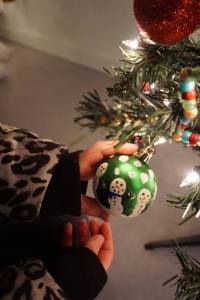 Pinky Sarber holds an ornament she made for a Christmas tree decorated by Paul Banks Elementary School students for a fundraiser Friday, Dec. 1, 2017 in Homer, Alaska benefitting South Peninsula Haven House. Young artists made the snowmen by tracing their fingers. Local nonprofits decorated trees that were auctioned off in a silent auction at a space Haven House uses for special events on Bunnell Avenue in Homer. (Photo by Michael Armstrong, Homer News)