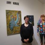 Amy Kruse poses for a photo at a First Friday reception on Dec. 1, 2017 at Fireweed Gallery in Homer, Alaska. Some of her fashion designs is on the mannequin at right. (Photo by Michael Armstrong, Homer News)