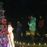 A small crowd of people pauses to watch the Homer High School Swing Choir perform Saturday, Dec. 16, 2017 at the Bear Creek Winery Garden of Lights near Homer, Alaska. (Photo by Megan Pacer/Homer News)
