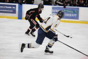 Kenai Central High School&rsquo;s Levi Mese skates with the puck under pressure from Homer&rsquo;s Spencer Warren during their game Thursday, Jan. 25, 2018 at the Kevin Bell Arena in Homer, Alaska. The Mariners beat the Cardinals in a tight game, coming out victorious 6-5. (Photo by Megan Pacer/Homer News)