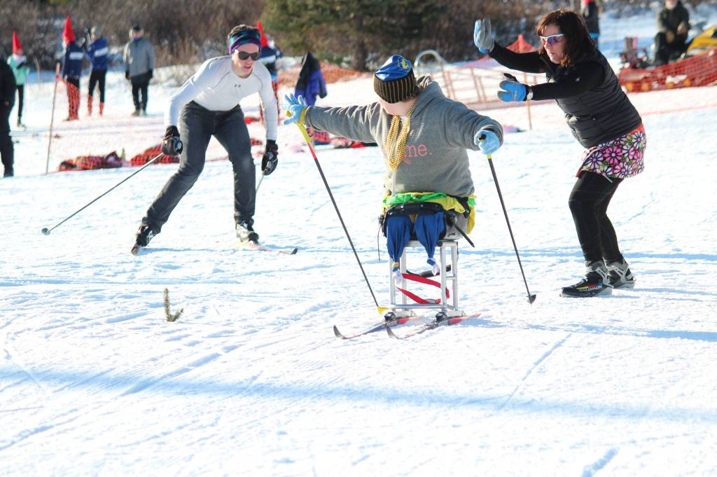 Angelica Haakenson reaches back for fellow Homer Nordic ski team member Denver Waclawski to tag her during an adaptive sit ski relay race Saturday, Feb. 3, 2018 at the Lookout Mountain Ski Trails. Four-person teams from Homer, Soldotna and Kenai used two sit skiers and two standing skiers to race around the trails Saturday after the individual skate races, with Homer coming out victorious. (Photo by Megan Pacer/Homer News)