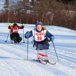 Angelica Haakenson skis to the finish line of the adaptive girls sit ski race ahead of Kenai junior Maria Salzetti on Friday, Feb. 2, 2018 at the Lookout Ski Trails near Homer, Alaska. Haakenson made her racing debut with the Homer Nordic ski team this year after losing her legs in a car accident three years ago. She took first place in the race. (Photo by Megan Pacer/Homer News)