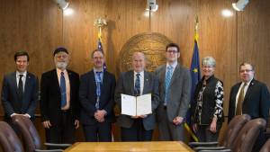 From left to right, Rep. Neal Foster, D-Nome; Rep. Paul Seaton, R-Homer; David Teal of the Legislative Finance Division; Gov. Bill Walker; Neil Steininger of the Office of Management and Budget; Sen. Anna MacKinnon, R-Eagle River; and Sen. Lyman Hoffman, D-Bethel are seen at the signing ceremony for House Bill 321 on Tuesday, March 27, 2018 in the governor&rsquo;s cabinet room of the Alaska State Capitol. (Drew Cason