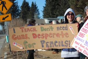 Homer Flex teacher Lindsay Martin holds a cardboard sign reading &ldquo;I teach. Don&rsquo;t need guns, desperate for pencils!&rdquo; at a rally to support the national March for Our Lives on Saturday, March 24, 2018 at WKFL Park in Homer, Alaska. Martin said she doesn&rsquo;t think those who suggest arming teachers do so out of malice, but that she does not see it as a viable solution to gun violence in schools. Dozens of Homer residents gathered with similar messages at the park Saturday in an impromptu rally organized by the Homer chapter of Citizens Action Network. (Photo by Megan Pacer/Homer News)