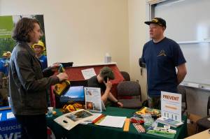 Homer High School student Ellie Syth, left, visits with wildland firefighter Aaron Seaton at the Alaska Division of Forestry table during the Kachemak Bay Campus College and Career Fair last Friday, March 30, 2018 in Homer, Alaska. About 400 students from 11 area schools as well as community members visited the annual event, said Kim Frost, KBC student and enrollment services coordinator. (Photo by Michael Armstrong/Homer News)